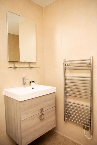 a bathroom with a sink and a mirror at Apt 3, Trafalgar Sq Duplex, 3rd & 4th floor by Indigo Flats in London