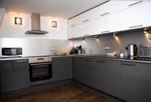 a kitchen with gray cabinets and a stove top oven at Apt 3, Trafalgar Sq Duplex, 3rd & 4th floor by Indigo Flats in London