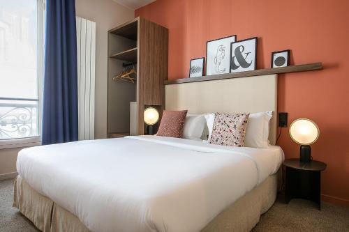 ein Schlafzimmer mit einem großen weißen Bett mit orangefarbenen Wänden in der Unterkunft Le Petit Belloy in Paris