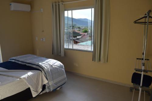 a bedroom with a bed and a window with a view at Apto Completo Praia Central Armação in Penha