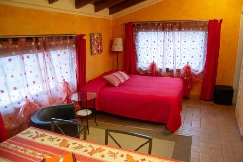 a bedroom with a red bed and two windows at L'Angolo Di Verlano in Canossa
