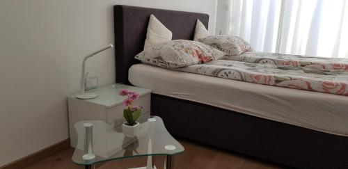 a bedroom with a bed with a night stand and a table at Vila Ema Apartments and Rooms in Ljubljana