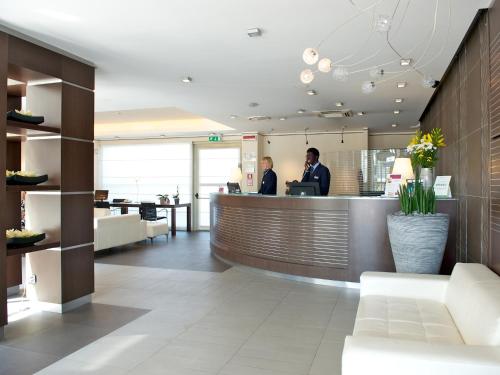 a lobby with two people standing at a counter at Mercure Bergamo Aeroporto in Stezzano