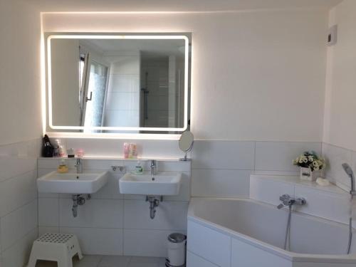 a white bathroom with two sinks and a mirror at Privatzimmer an der Messe in Hannover