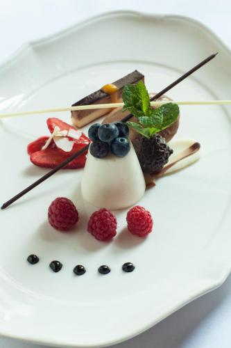 a white plate with a dessert with berries on it at Parkhotel Oberstaufen in Oberstaufen