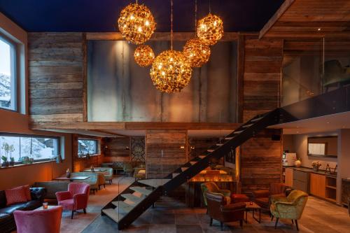 a lobby of a restaurant with a staircase and chandeliers at 22 Summits Boutique Hotel in Zermatt