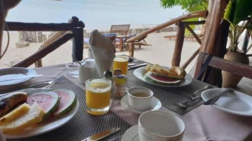 een tafel met borden en twee glazen bier bij Menai Bay Beach Bungalows in Unguja Ukuu