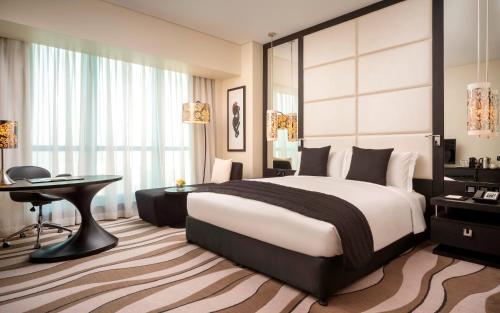 a hotel room with a large bed and a desk at Sofitel Abu Dhabi Corniche in Abu Dhabi