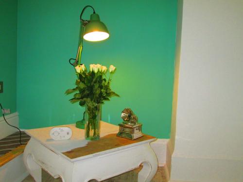 a vase of flowers on a table with a lamp at Weston Manor in Freshwater