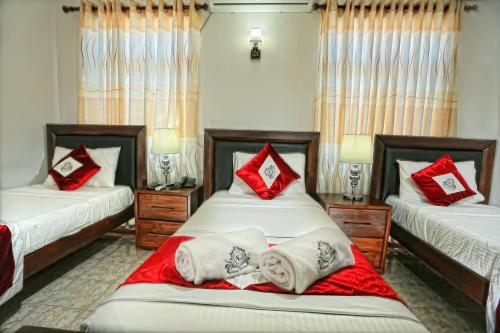 Un dormitorio con dos camas con almohadas rojas y blancas. en Asian Grand Hotel, en Negombo