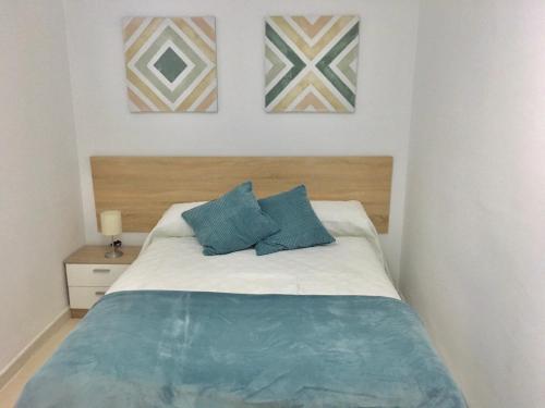 ein Schlafzimmer mit einem Bett mit zwei blauen Kissen in der Unterkunft Apartamento Pasaje Ronda Centro in Ronda