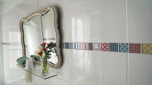 a bathroom with a mirror and a vase with flowers on a shelf at Hotel des Dames in Nice
