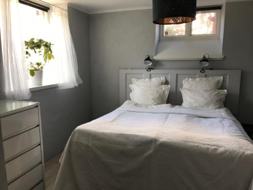 um quarto com uma cama com lençóis brancos e almofadas em Charmigt i centrala Ystad em Ystad