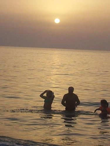 a group of people in the water at sunset at IN CENTRO ROOMS Vicino Cefalù SELF-CHEK-IN in Campofelice di Roccella