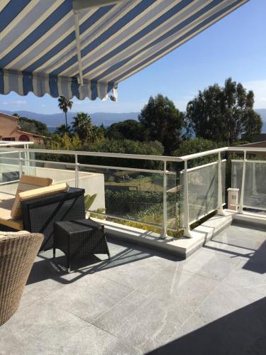 a patio with a blue and white umbrella and chairs at Villa cote plage in Ajaccio