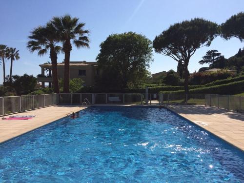 une piscine avec des palmiers et une maison dans l'établissement Appartement 1 chambre vue mer au Clos de la Madrague, à Sainte-Maxime