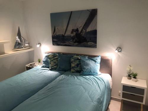 - une chambre dotée d'un lit avec des draps bleus et une peinture murale dans l'établissement Appartement 1 chambre vue mer au Clos de la Madrague, à Sainte-Maxime