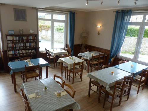 une salle à manger avec tables, chaises et fenêtres dans l'établissement Le Yaudet, à Ploulech