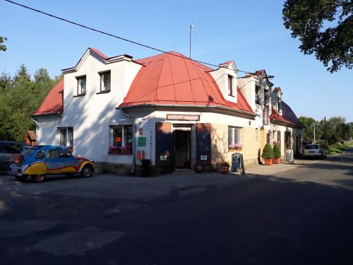 um carro estacionado em frente a um edifício com um telhado vermelho em Pension u Adršpachu - Dana Tyšerová em Janovice