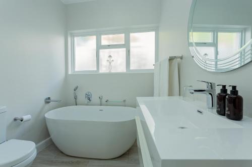 a white bathroom with a large tub and a sink at Tehillah Guest House in George