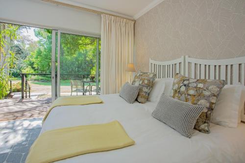 a bedroom with a large white bed and a balcony at Tehillah Guest House in George