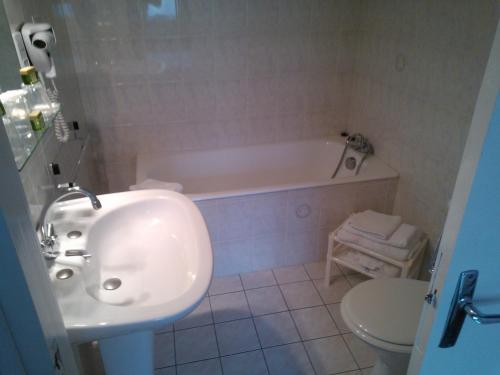 La salle de bains est pourvue d'un lavabo, d'une baignoire et de toilettes. dans l'établissement Logis Le Franco Belge, à Monthermé