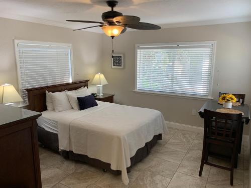 a bedroom with a bed with a ceiling fan and two windows at Twin Palms at Siesta in Siesta Key