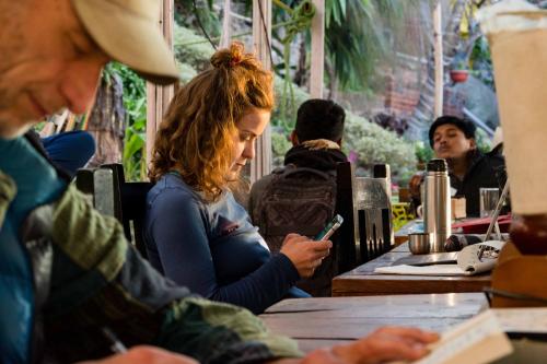 a woman sitting at a table looking at her cell phone at Wander Thirst in Kathmandu