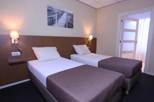 a hotel room with two beds and a window at Hotel Restaurant De Bengel in Eersel
