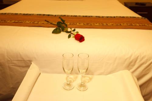 two wine glasses on a table in front of a bed at Casa Suyay in Lima