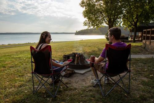 a man and a woman sitting in chairs around a fire at Lewis & Clark Resort in Yankton