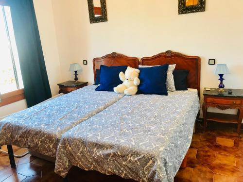 a teddy bear sitting on a bed with blue pillows at La Aldea in Aldea del Fresno