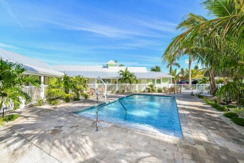 a swimming pool with palm trees in front of a house at Tropical Breeze Resort in Siesta Key