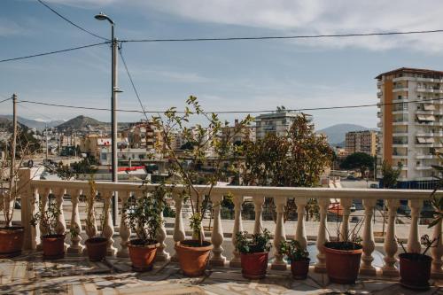 a white railing with potted plants on a balcony at Elti Apartment in Sarandë