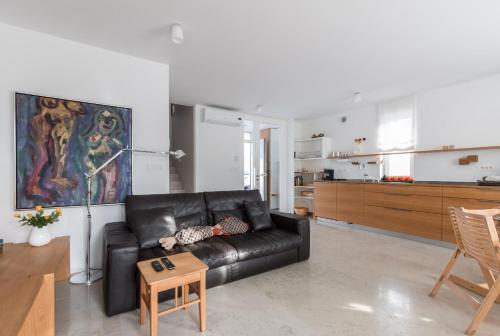 a living room with a black leather couch and a table at Apartment Beta in Izola