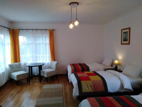 a bedroom with two beds and a table and a chair at Hostería Pionero in Cerro Castillo