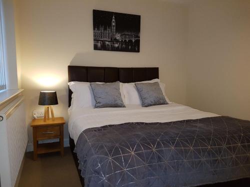 a bedroom with a bed and a lamp on a table at Moorland House in Syston