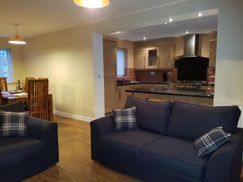 a living room with a couch and a kitchen at Moorland House in Syston