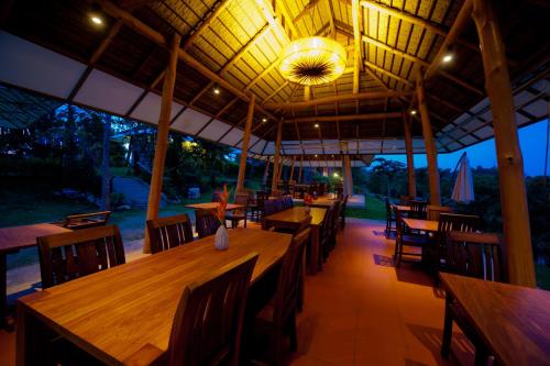 a restaurant with wooden tables and chairs and a ceiling at Phukumhom Khao Yai in Wangkata