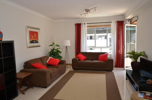 een woonkamer met twee bruine banken en rode kussens bij Expo Marina Lis in Lissabon