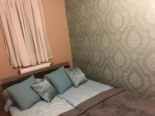 um quarto com uma cama com três almofadas em Sugárút Corner Apartman em Debrecen