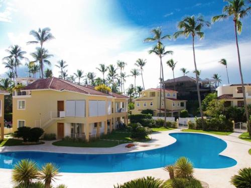a villa with a swimming pool and palm trees at Tropical Villas at Los Corales Beach - Caribbean Rentals FZCO in Punta Cana