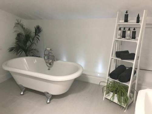 baño con bañera blanca y planta en Ye Olde Saddlery B&B, en Neatishead