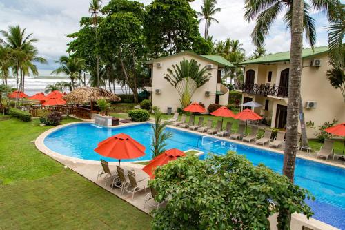 a resort with a swimming pool with chairs and umbrellas at Club del Mar Oceanfront in Jacó