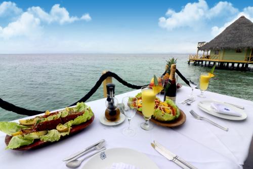 a table topped with plates of food on top of a beach at Punta Caracol Acqua Lodge in Bocas Town