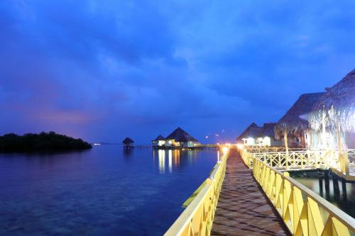 a pier with houses on the water at night at Punta Caracol Acqua Lodge in Bocas del Toro