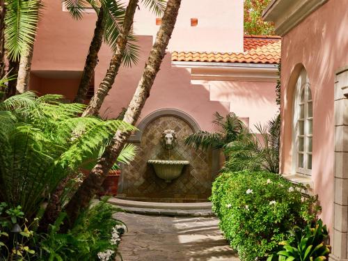 a fountain in the side of a building with palm trees at Hotel Bel-Air - Dorchester Collection in Los Angeles