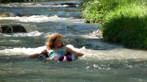 a little girl sitting in the water in a river at Allen Ranch in Hot Springs