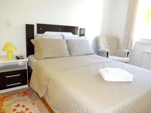 1 dormitorio con 1 cama grande y 1 silla en Apartamento Aconchegante + Bikes, en Gramado