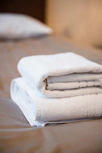 a stack of white towels stacked on a bed at Bestes apartamenti in Kocēni